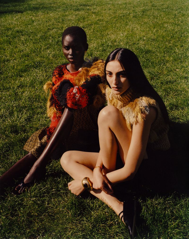 Avanti Nagrath and Nyanderi Deng seated together on green grass wearing textured knitwear for British Vogue.