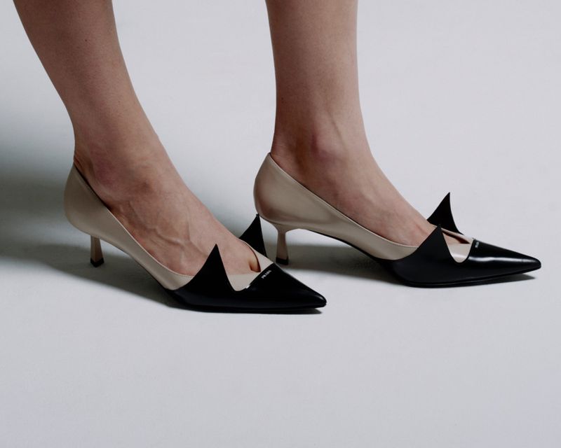 Elegant women's heels. Pair of two-tone, black and beige leather stiletto heel pumps on a plain white background. Classic and modern footwear.