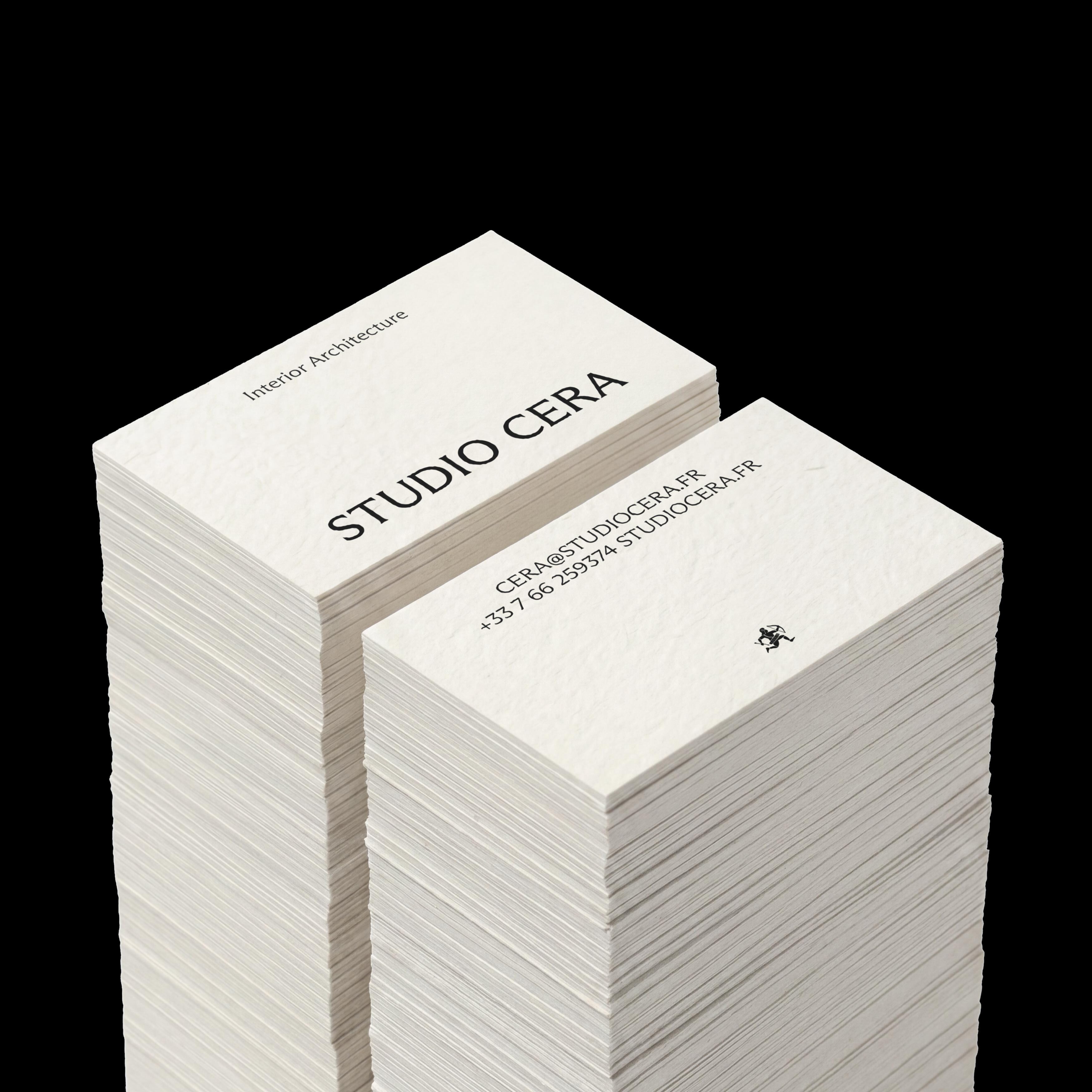 Two tall stacks of textured cream business cards for Studio Cera set against a solid black background.