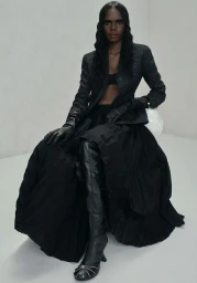 Model Tarlisa Gaykamangu in a black jacket, leather gloves and boots seated against a white seamless backdrop for Vogue Australia