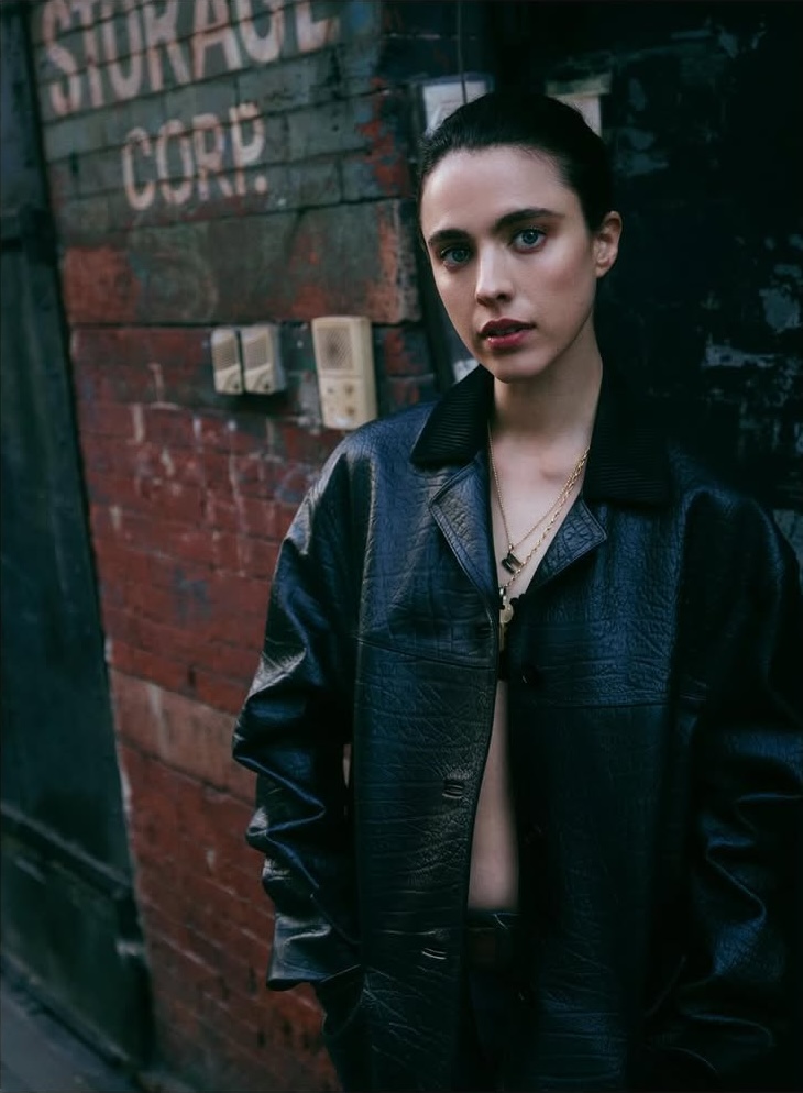 Margaret Qualley wearing a black leather jacket against a weathered brick wall for Vogue Australia.