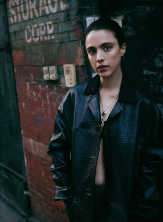 Margaret Qualley wearing a black leather jacket against a weathered brick wall for Vogue Australia.