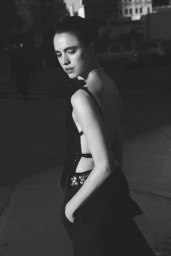 Black and white portrait of Margaret Qualley in a dark cutout top outdoors at dusk for Vogue Australia