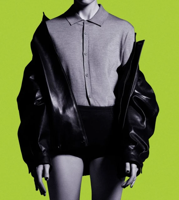 Cropped studio portrait of an adult female in a grey sweater, black jacket, and bottoms against a vibrant lime green background.