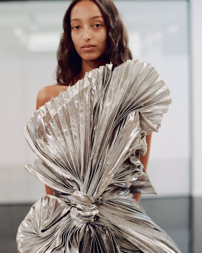 Model wearing a pleated silver metallic haute couture dress by Dior with a sculptural fan bodice.