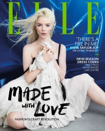 Anya Taylor-Joy kneeling in a layered white lace dress against a vivid blue backdrop for the cover of Elle UK.