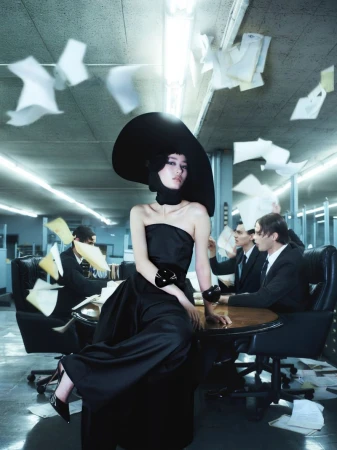 Elegant woman in a black dress and hat sits on a table surrounded by suited men in a modern office filled with floating papers.