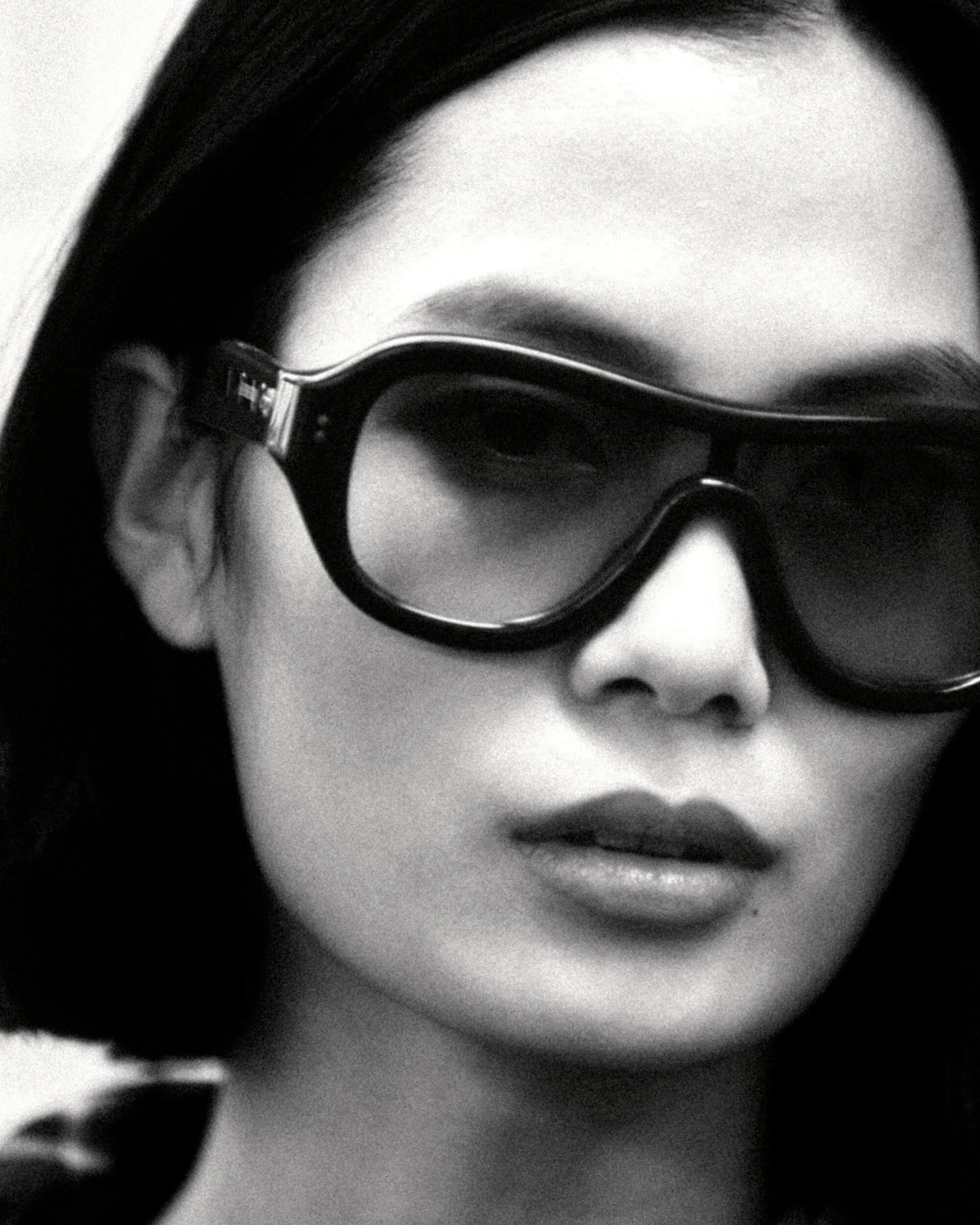 Black and white close-up portrait of model Haojie Qi wearing oversized black sunglasses for Burberry.
