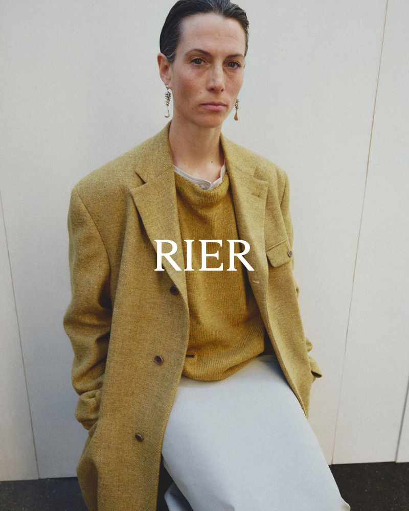 Model wearing an oversized mustard yellow wool coat and matching knit sweater against a neutral studio backdrop.