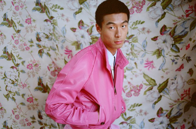Model Yan Li wearing a bright pink leather jacket in front of a vintage floral print fabric backdrop for Esquire China.