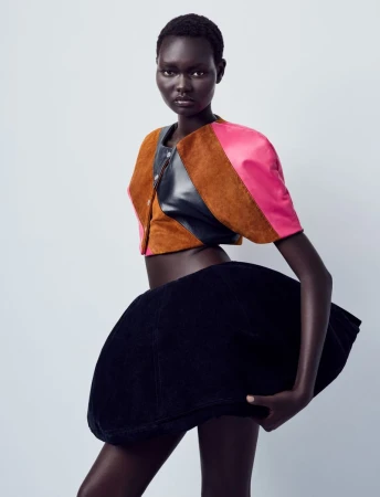Model Ateta Jok wearing a structured pink, brown, and black crop top with an exaggerated black balloon skirt against a pale background.