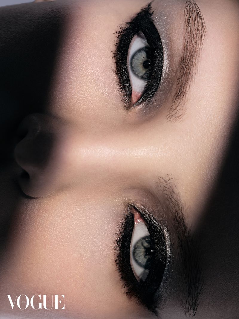Extreme close-up of a person's eyes with thick black eyeliner, light skin tone, and soft, dramatic shadows in a portrait.
