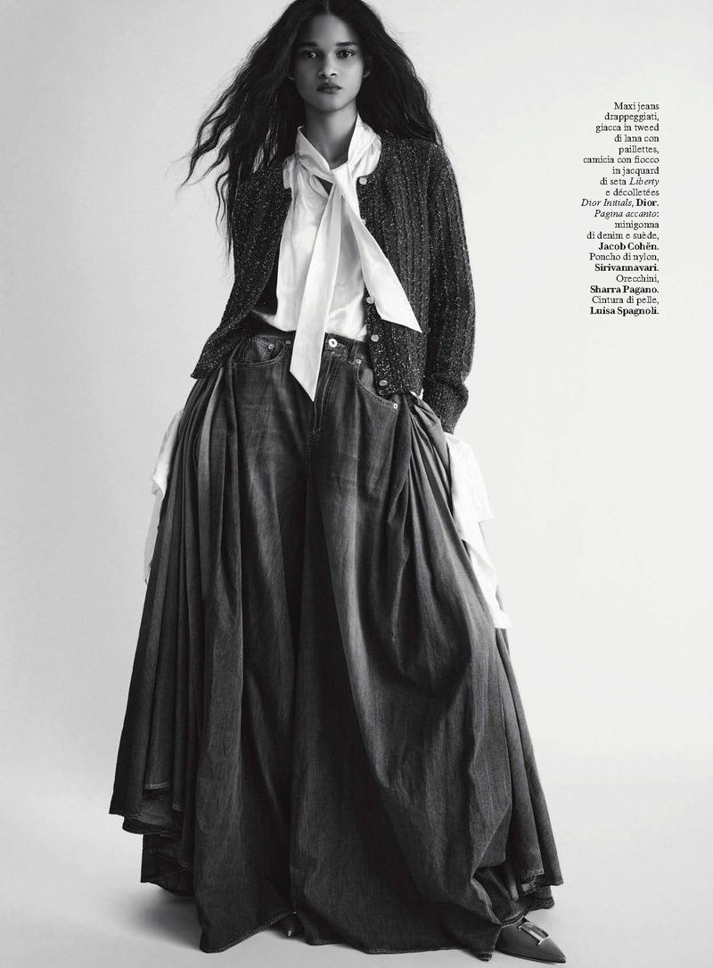Model in dark cardigan over white blouse and voluminous denim skirt against seamless white