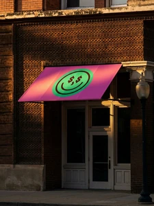 Pink storefront awning featuring a green circular smiley face logo with dollar sign eyes on a brown brick facade.