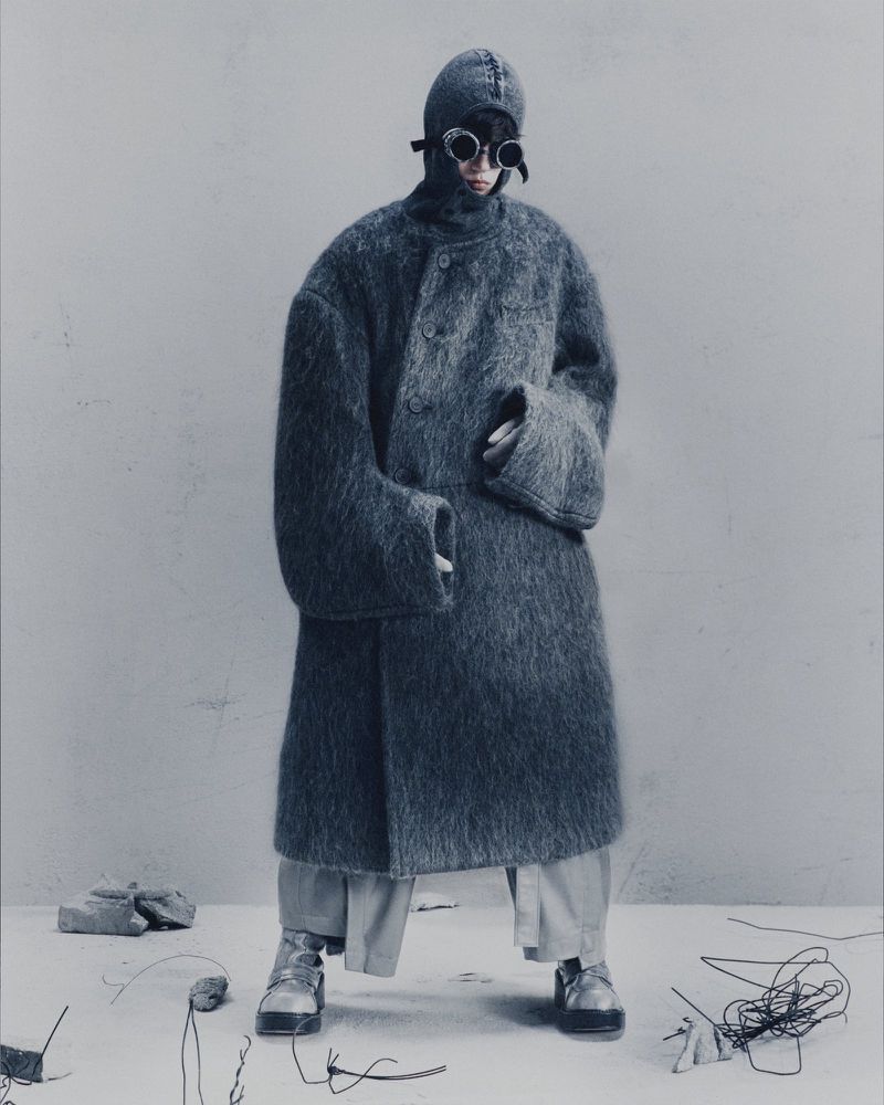 Park Seonghwa wearing an oversized fuzzy charcoal coat, matching balaclava hood, and goggles in a Songzio campaign.
