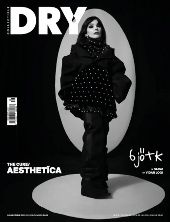 Magazine cover features Bjork in a polka dot top and oversized coat, posed against a black background with geometric spotlights.