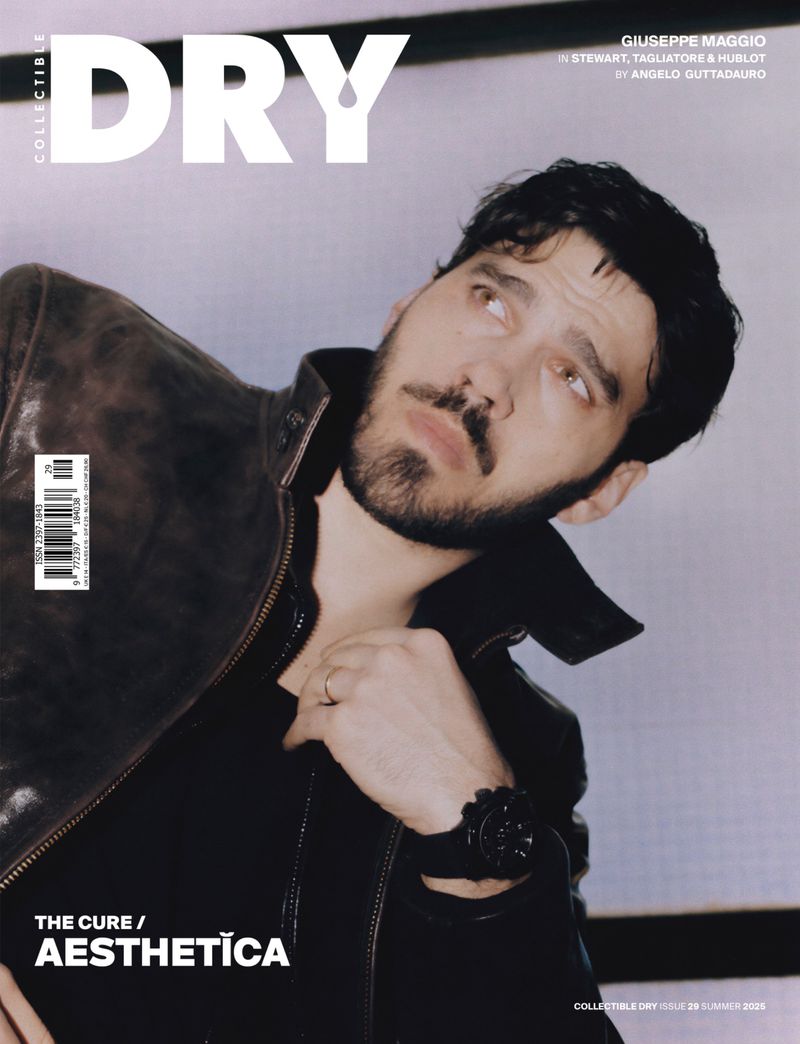 Magazine cover featuring a man with dark hair and a beard wearing a leather jacket and a black shirt, looking upward.