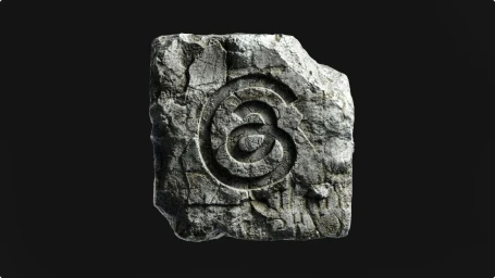 Carved stone block featuring the embossed Threads logo emblem centered against a solid black background.