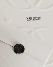 Off-white paper envelope sealed with a stamped black wax seal against an embossed background with text reading Where Comfort Becomes Form.