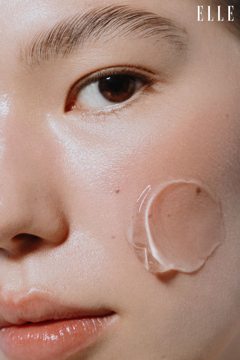 Close-up portrait of an East Asian woman's face featuring a circular swatch of clear skincare gel applied to her cheek.