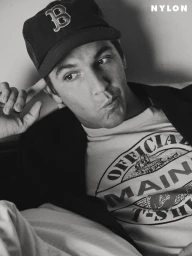 Black and white portrait of musician Role Model wearing a dark baseball cap and graphic t-shirt for Nylon Guys.