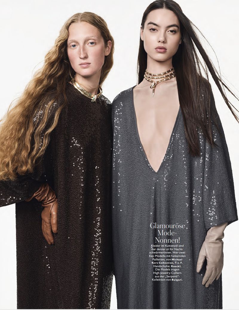 Two fashion models pose in sequined dresses and gloves against a stark white background, accessorized with gold chokers, for a studio editorial.