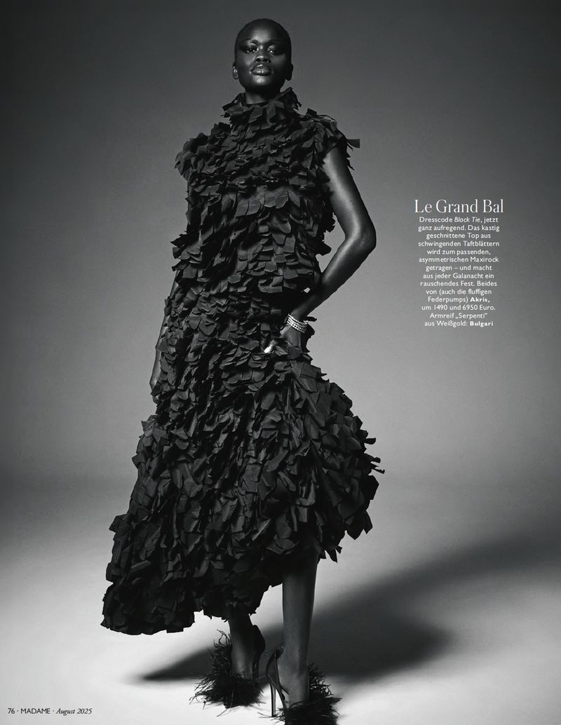 Editorial fashion shot of an African woman in a ruffled black dress with heels in a studio with gradient gray background. 