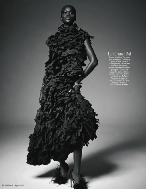Editorial fashion shot of an African woman in a ruffled black dress with heels in a studio with gradient gray background. 