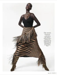 Model in a black camisole and patterned fringed skirt against a white studio background.