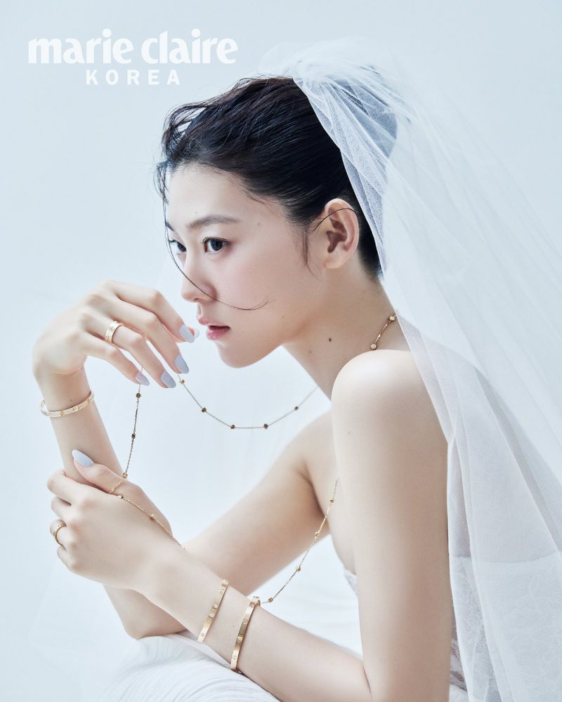 Model Sol Jeong wearing a sheer white bridal veil and fine gold jewelry against a white studio background.