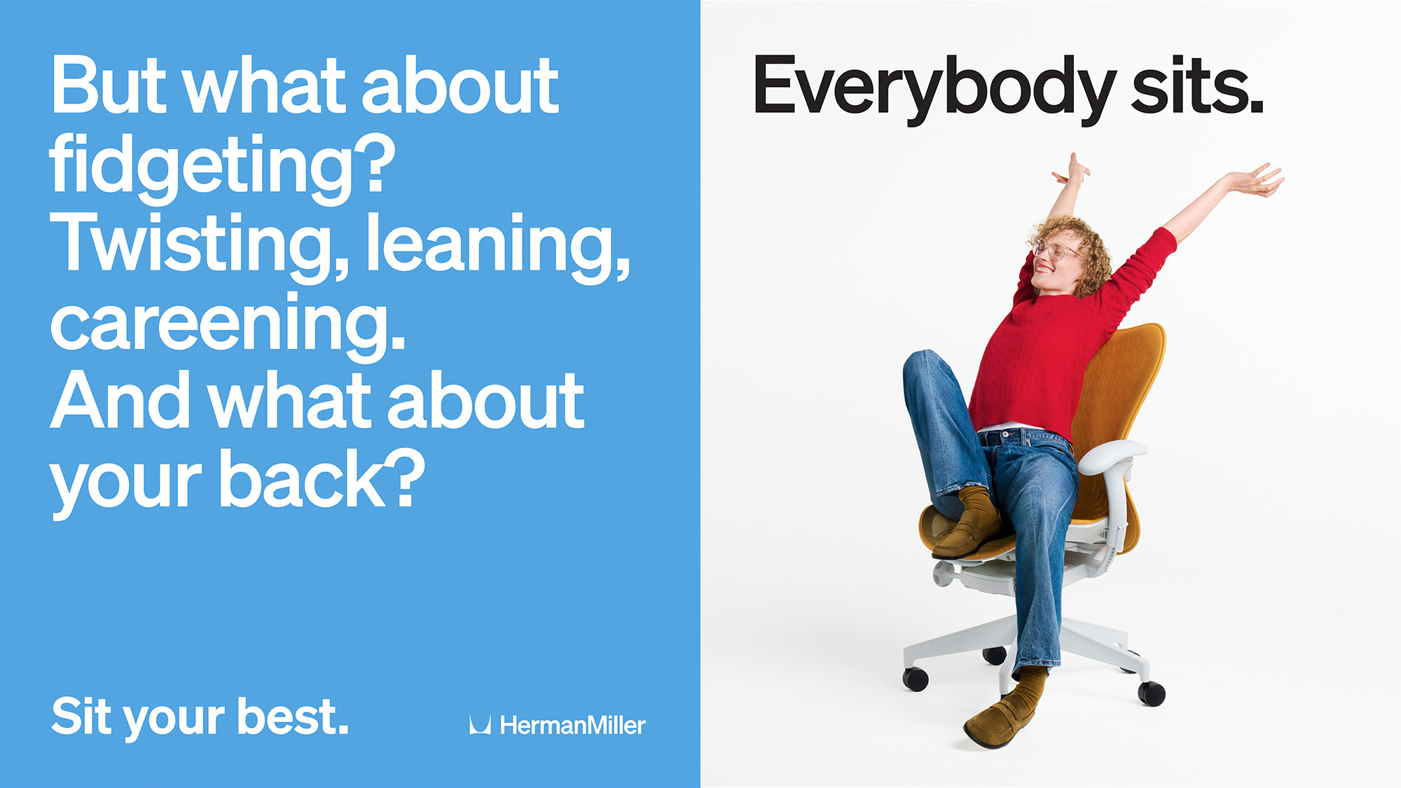 A person with curly hair wearing a red long-sleeved shirt and jeans sitting in an ergonomic office chair with arms raised on white background.