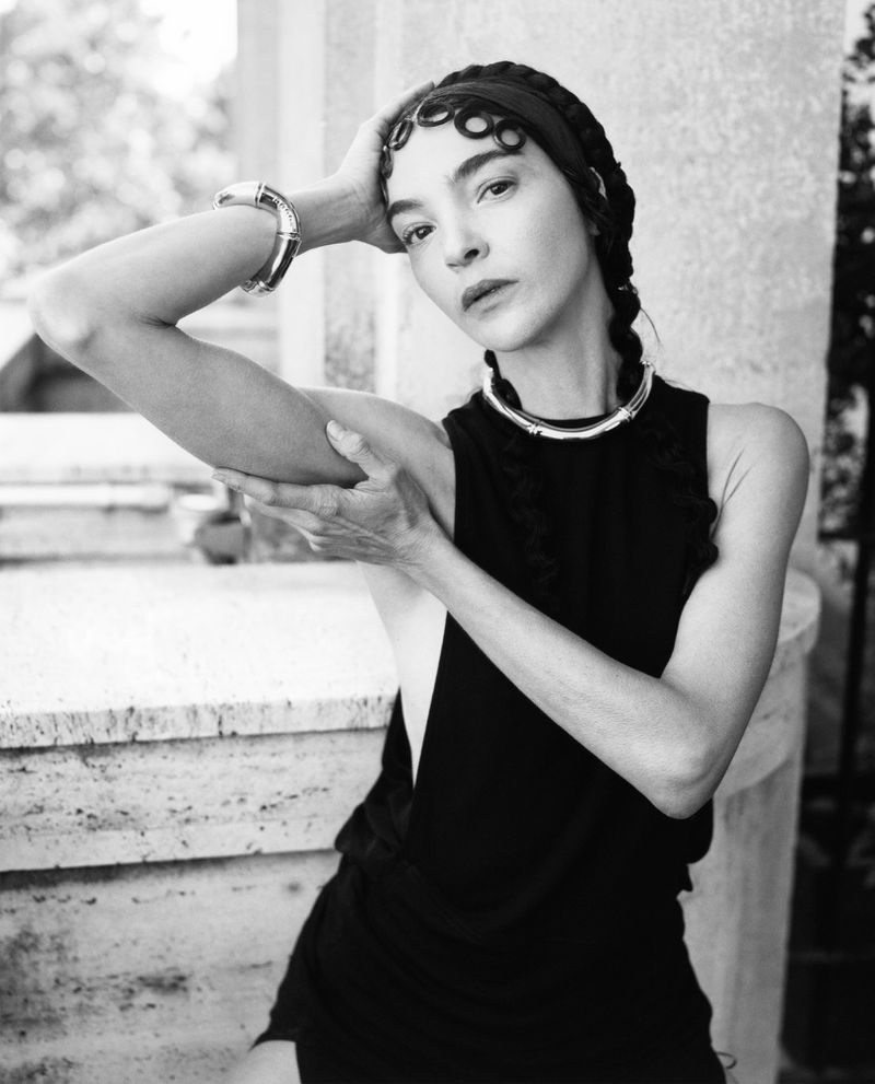 Model Mariacarla Boscono wearing a black sleeveless top, silver collar necklace, and sculpted finger waves in a black and white portrait.