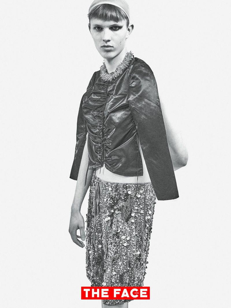 Model wearing a ruched dark jacket and embellished sequin trousers against a white seamless background for The Face.