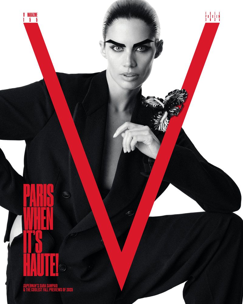 V Magazine cover featuring a woman in a black suit kneeling against a white background with a large red 'V' overlay.