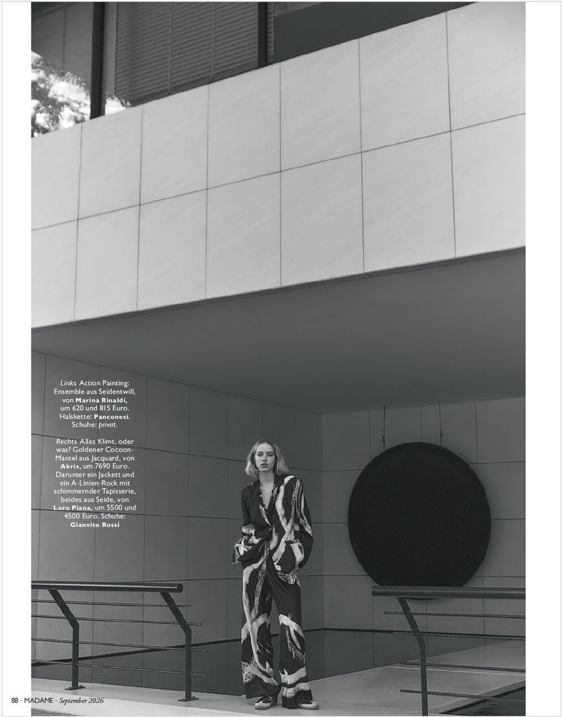 Sylwia Kuta stands in a patterned brushstroke pantsuit before a grid wall and large circular art installation.