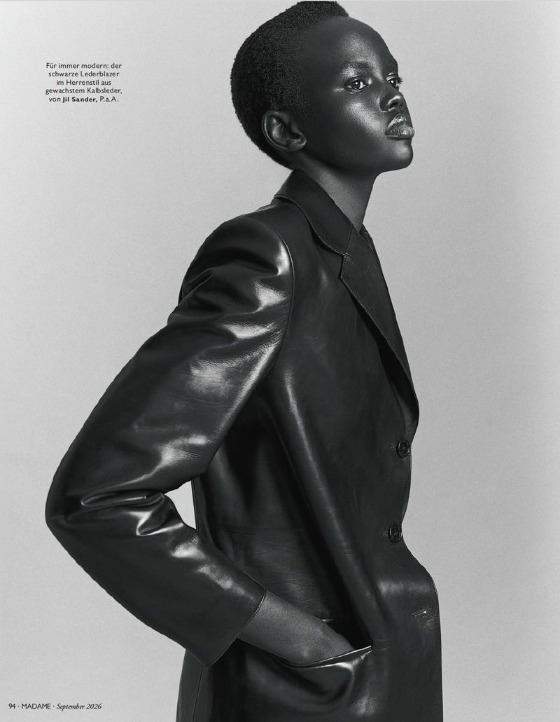 Model Ajak Dhieu posing in a tailored black leather blazer against a studio backdrop in a black and white profile portrait.