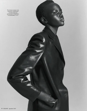 Model Ajak Dhieu posing in a tailored black leather blazer against a studio backdrop in a black and white profile portrait.