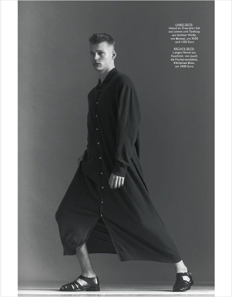 Model Timo Pan wearing a long black button-down cashmere robe shirt and caged leather sandals against a studio backdrop.