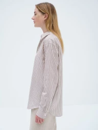 Model in profile wearing a brown and white striped collared shirt against a white seamless background.