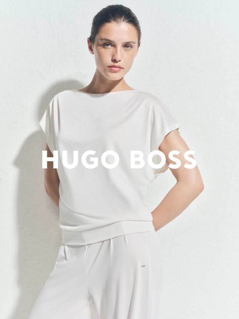 Model Emma Todt wearing a white boatneck top and matching white trousers against a white textured background for BOSS.