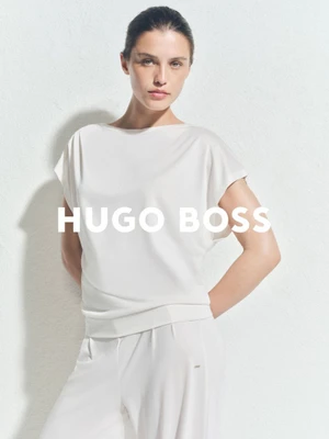 Model Emma Todt wearing a white boatneck top and matching white trousers against a white textured background for BOSS.