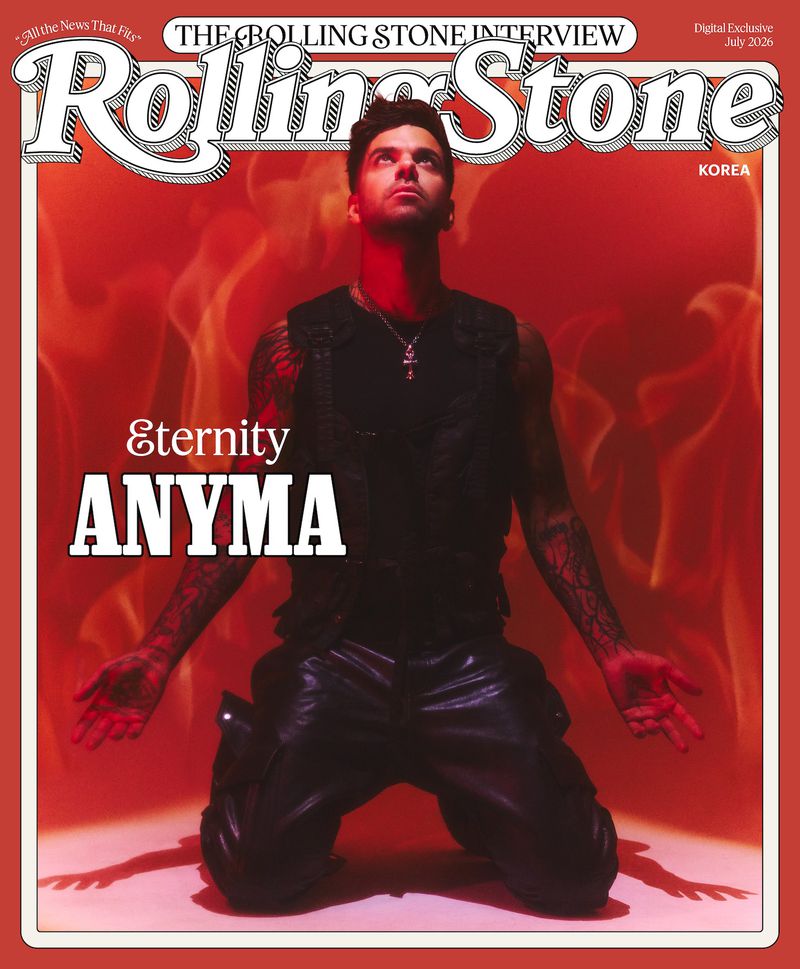Anyma kneeling in a black tactical vest against a bright red flame-patterned backdrop for a Rolling Stone Korea cover feature.