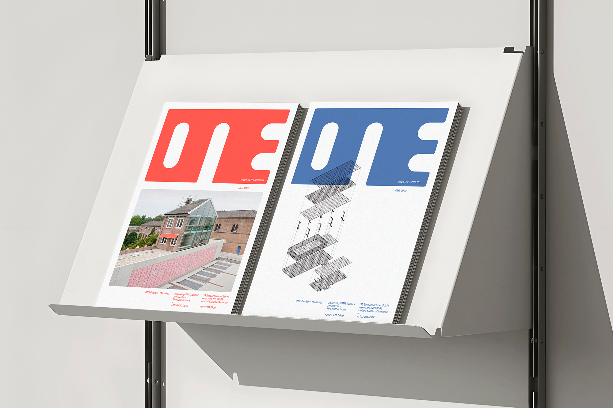 Two architectural magazines labeled ONE displayed on a white metal rack against a plain light grey studio background.