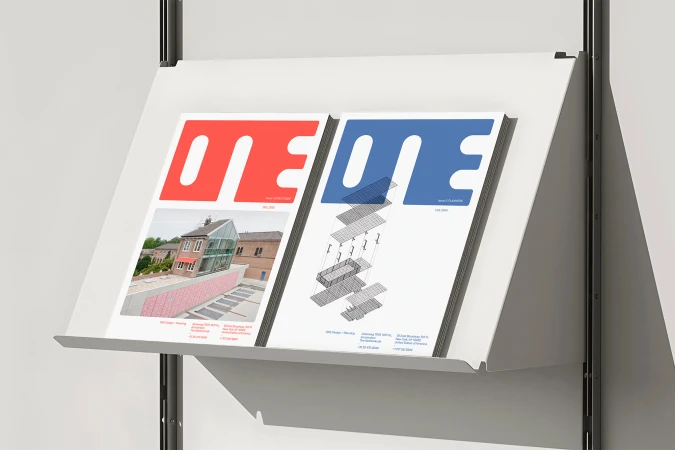 Two ONE urban practice booklets with red and blue typography displayed on a white metal wall-mounted shelf.