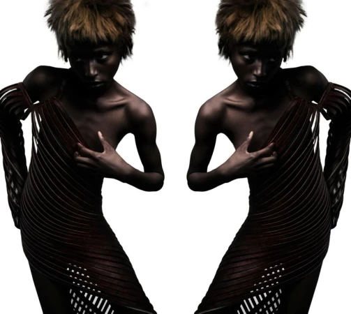 Mirrored studio portrait of model Blessing Ifeoluwa wearing a dark ribbed sculptural dress against a pure white background.