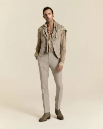 Model Pawel Binczak in a tailored beige vest, trousers, and patterned shirt on a cream backdrop for John Varvatos.