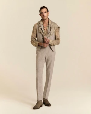 Model Pawel Binczak in a tailored beige vest, matching trousers, and patterned shirt on a warm studio backdrop.