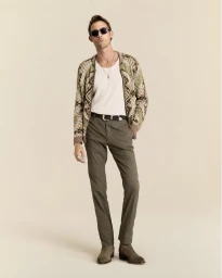 Model Pawel Binczak wearing a patterned knit cardigan, white tank top, tailored trousers, and sunglasses against a beige backdrop.
