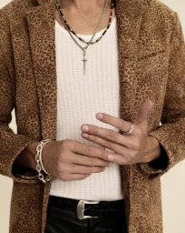 Cropped view of a model wearing a brown leopard print jacket, white ribbed tank top, layered silver necklaces, and bracelet.