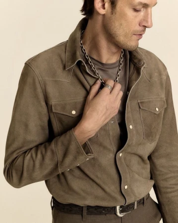 Model Pawel Binczak wearing a brown suede western shirt and silver chain necklace against a pale backdrop.